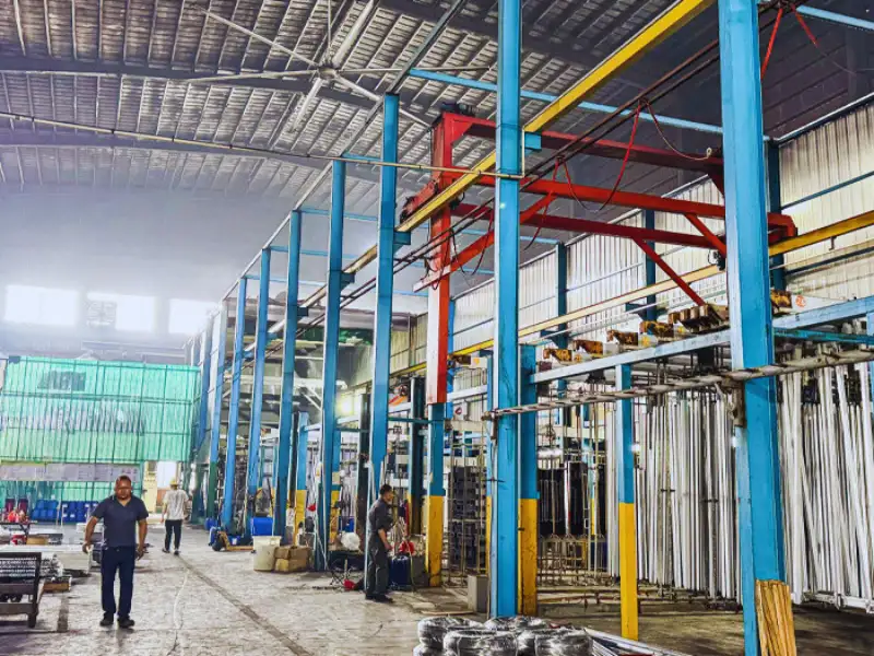 Trabajadores en el taller de fabricación de una línea de producción de anodizado de perfiles de aluminio industrial.